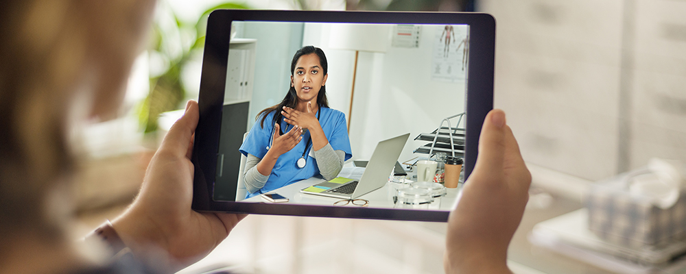 Person holding tablet showing a doctor on the screen